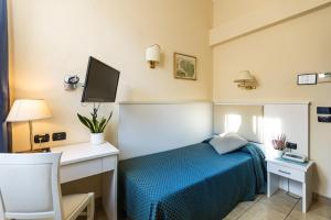 ein Schlafzimmer mit Bett, Schreibtisch und Fernseher in der Unterkunft Hotel Stella in Rapallo