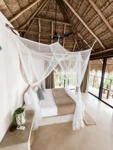 a bedroom with a bed with a mosquito net at Ikal Bungalows Tulum in Tulum