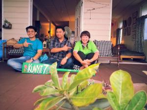 three people sitting on the porch of a house at Kunyit 7 Lodge in Bandar Seri Begawan