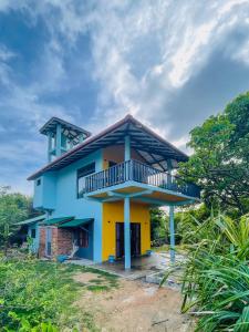 a blue and yellow house with a balcony at Turtle Breeze Rekawa in Tangalle