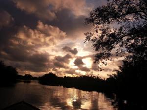 a sunset on a river with a cloudy sky at Kunyit 7 Lodge in Bandar Seri Begawan