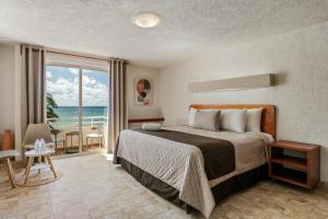 a bedroom with a bed and a view of the ocean at Luciana Hotel & Beach Club in Playa del Carmen