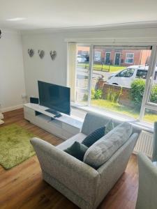 a living room with a couch and a flat screen tv at Contractors , holiday house, free parking , sleeps 5 in Knowsley
