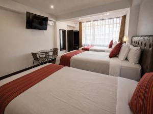 a hotel room with two beds and a table at Hotel Sky Mirador in Cusco