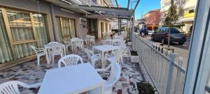 a row of tables and white chairs on a sidewalk at Hotel Astoria in Riccione +17 photos