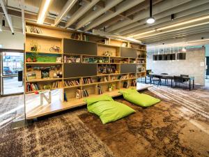 a room with a large book shelf with green pillows at Novotel Wrocław Centrum in Wrocław