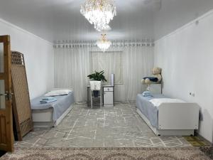 a bedroom with two beds and a chandelier at Friendly House in Bokonbayevo