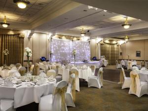 a banquet hall with white tables and white chairs at Mercure Dartford Brands Hatch Hotel & Spa in Dartford +54 photos