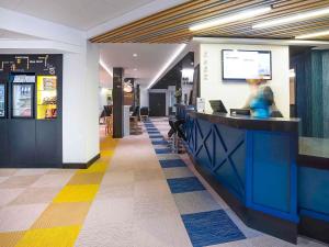 a restaurant lobby with a woman sitting at a counter at ibis Styles Deauville Centre in Deauville