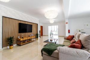 a living room with a couch and a flat screen tv at Castelo Sereno in Quinta do Conde