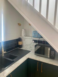 a kitchen with a sink and a microwave under a staircase at Peaceful Self-Contained Apartment in Beckenham