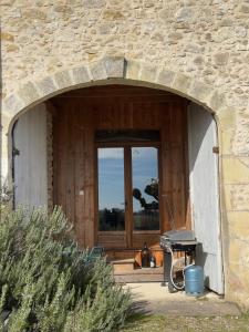 a stone building with a door and a grill at Les Foucauds in Saint-Quentin-de-Caplong