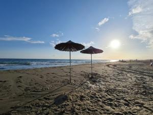 two umbrellas in the sand on a beach at Vila Eriona in Baks-Rrjoll