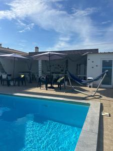 a swimming pool with umbrellas and a hammock at Bungalow Azul Profundo in Palmela