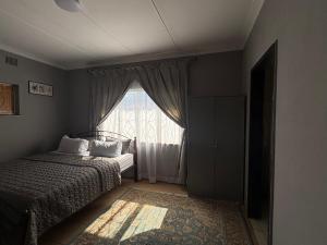 a bedroom with a bed and a window at Phapel Home-Away in Pretoria