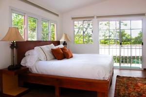 a bedroom with a bed with white sheets and windows at Nan La Tigra in El Rosario