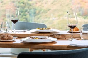 a wooden table with wine glasses and plates of food at Arantza Hotela - Boutique Hotel "Adults Only" in Arantza