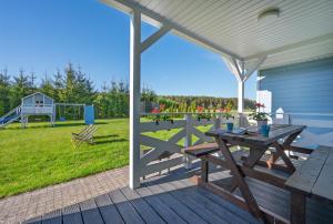a wooden deck with a picnic table and a playground at Domki PoZdrowie in Rusinowo