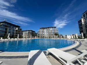 a large swimming pool with lounge chairs and buildings at Sea Breeze Polo in Nardaran