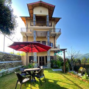 a house with a table and chairs and an umbrella at The Aalayam in Mukteshwar
