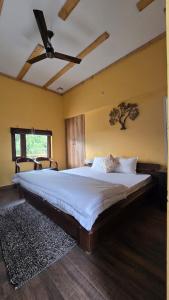 a bedroom with a large bed with a tree on the wall at The Aalayam in Mukteshwar