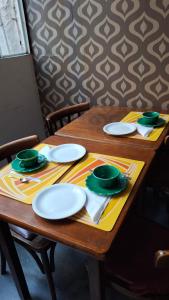 a wooden table with white plates and green dishes on it at Balcones de Cabrera in Buenos Aires
