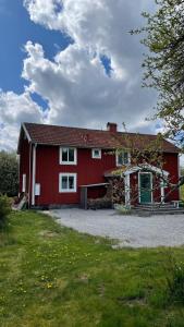 a red barn with a driveway in front of it at Villa Barkaboda in Barkaboda