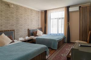 a hotel room with two beds and a window at Tashrabat Hotel in Karakol