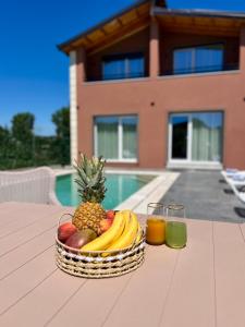 a basket of fruit on a table with two glasses of juice at Sunset Aura Riverside Villa & Pool in Draç
