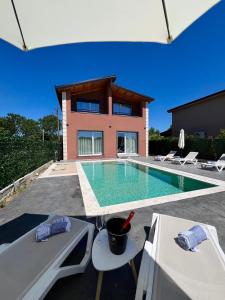 a house with a swimming pool in front of a house at Sunset Aura Riverside Villa & Pool in Draç