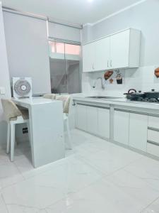 a white kitchen with white cabinets and a table at Montecarlo Hospedaje in Tacna