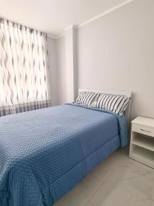 a bedroom with a bed with a blue blanket and a window at Montecarlo Hospedaje in Tacna