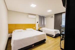 a hotel room with two beds and a window at Hotel Move BH in Belo Horizonte