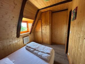 a bedroom with a bed in a wooden cabin at L'Oustalou de Petit Jean in Cassaniouze