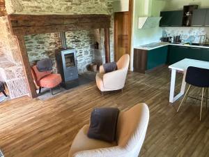 a living room with a fireplace and chairs and a table at L'Oustalou de Petit Jean in Cassaniouze