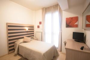 ein weißes Schlafzimmer mit Bett und Fernseher in der Unterkunft Stilhotel in Signa