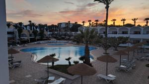 a view of a resort pool with chairs and umbrellas at Hôtel Hammamet Beach in Hammamet