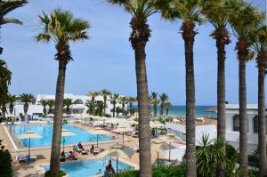 a view of the pool and ocean from the balcony of a resort at Hôtel Hammamet Beach in Hammamet