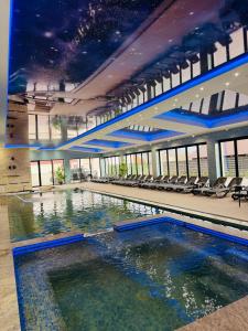 a large swimming pool in a building with chairs at Leo Resort and Spa in Petrova
