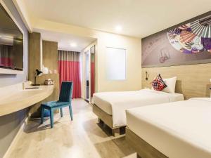 a hotel room with two beds and a chair at Ibis Styles Bangkok Sukhumvit 50 in Bangkok +74 photos