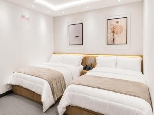 two beds in a room with white walls at Hotel Arkam in San Salvador
