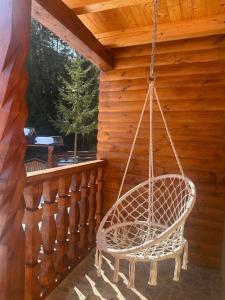 a swinging chair on the porch of a cabin at Cabana Luciana in Dămuc