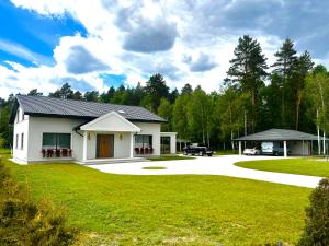 a white house with a driveway and a yard at American Dream Villa in Łazory