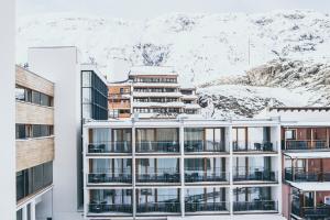 a building with snow covered mountains in the background at The Crystal VAYA Unique in Obergurgl