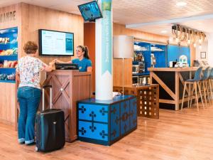 two women standing at a counter in a store at ibis Styles Carcassonne La Cité in Carcassonne