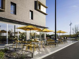a group of tables and chairs with yellow umbrellas at ibis Styles Versailles Guyancourt in Guyancourt