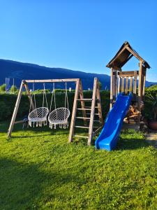a playground with a slide and a swing at Blumenpension Strauss - Ferienwohnungen in Ossiach