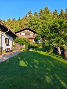 a yard with a house with a grassy yard at Blumenpension Strauss - Ferienwohnungen in Ossiach