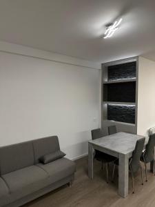 a living room with a couch and a table and chairs at Grey loft in Torvaianica