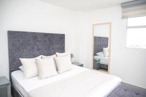 a white bedroom with a large bed with white pillows at Ginebra central laureles estadio in Medellín